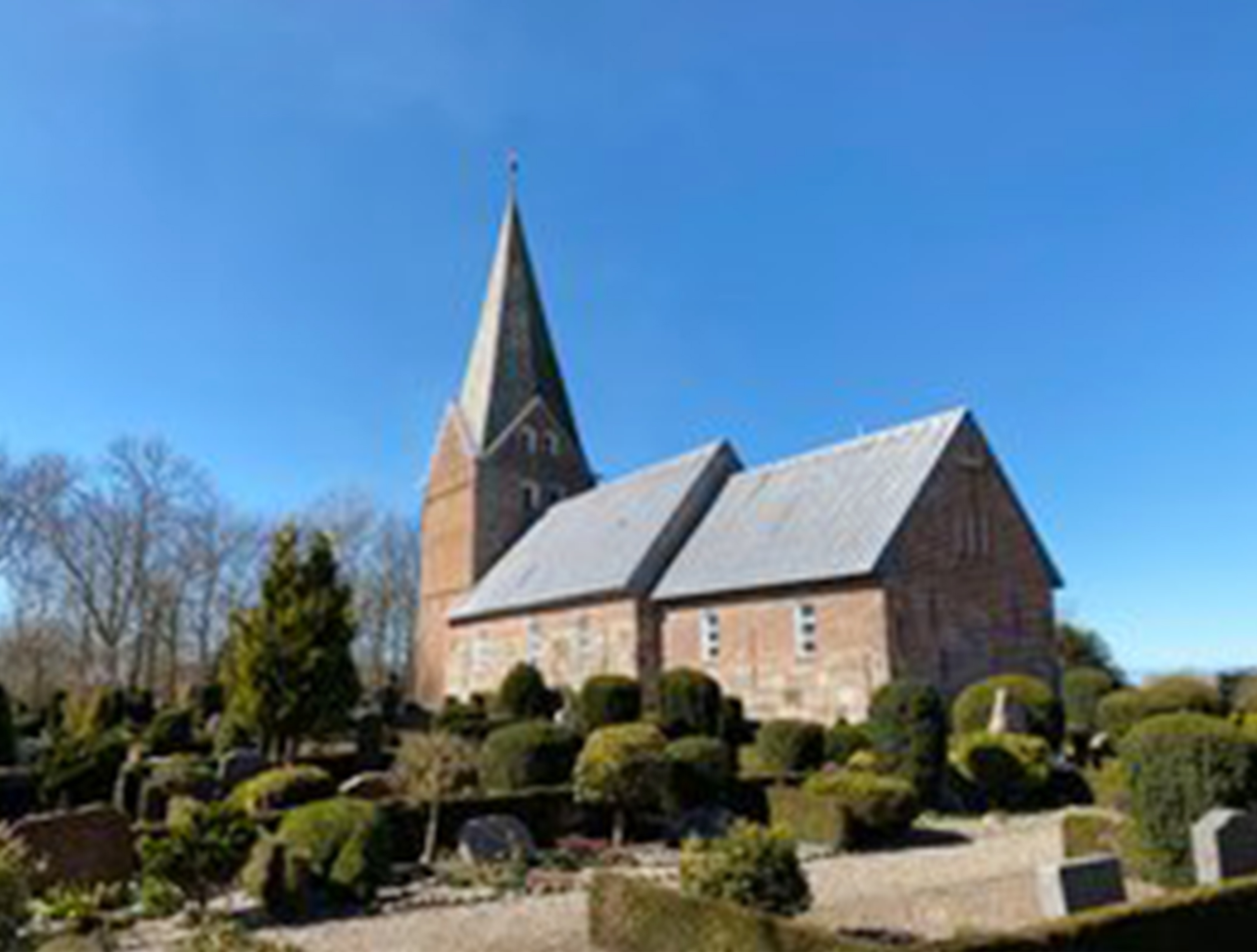 Billede af Daler Kirke med rødt murværk og spidst tårn.