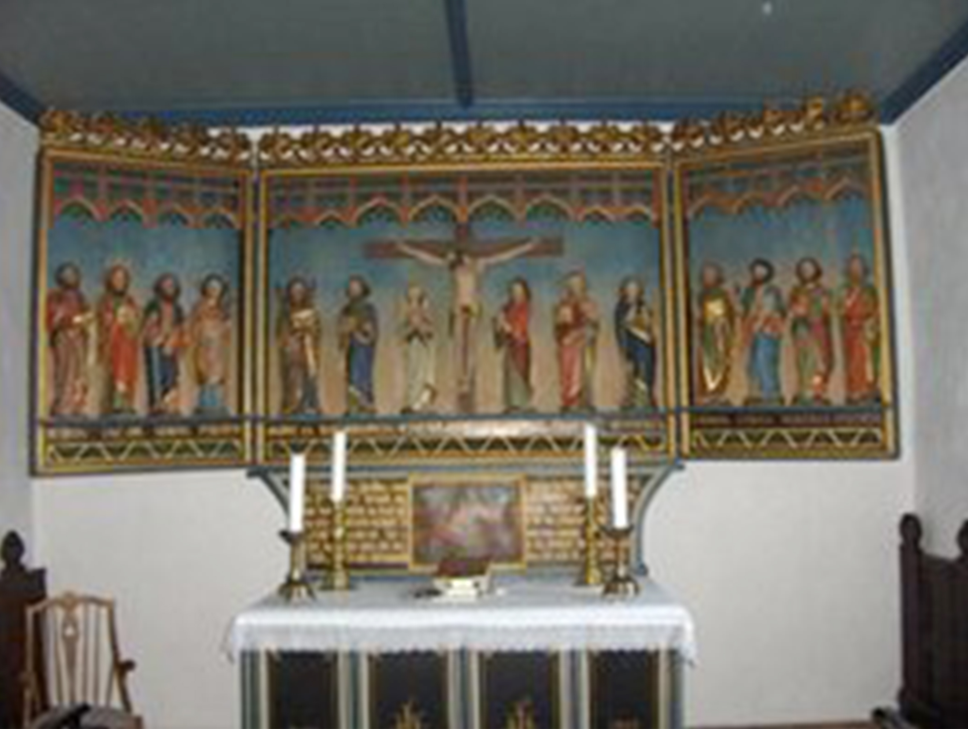 Billede af et farverigt alter med udskårne figurer og et krucifiks i en kirke.